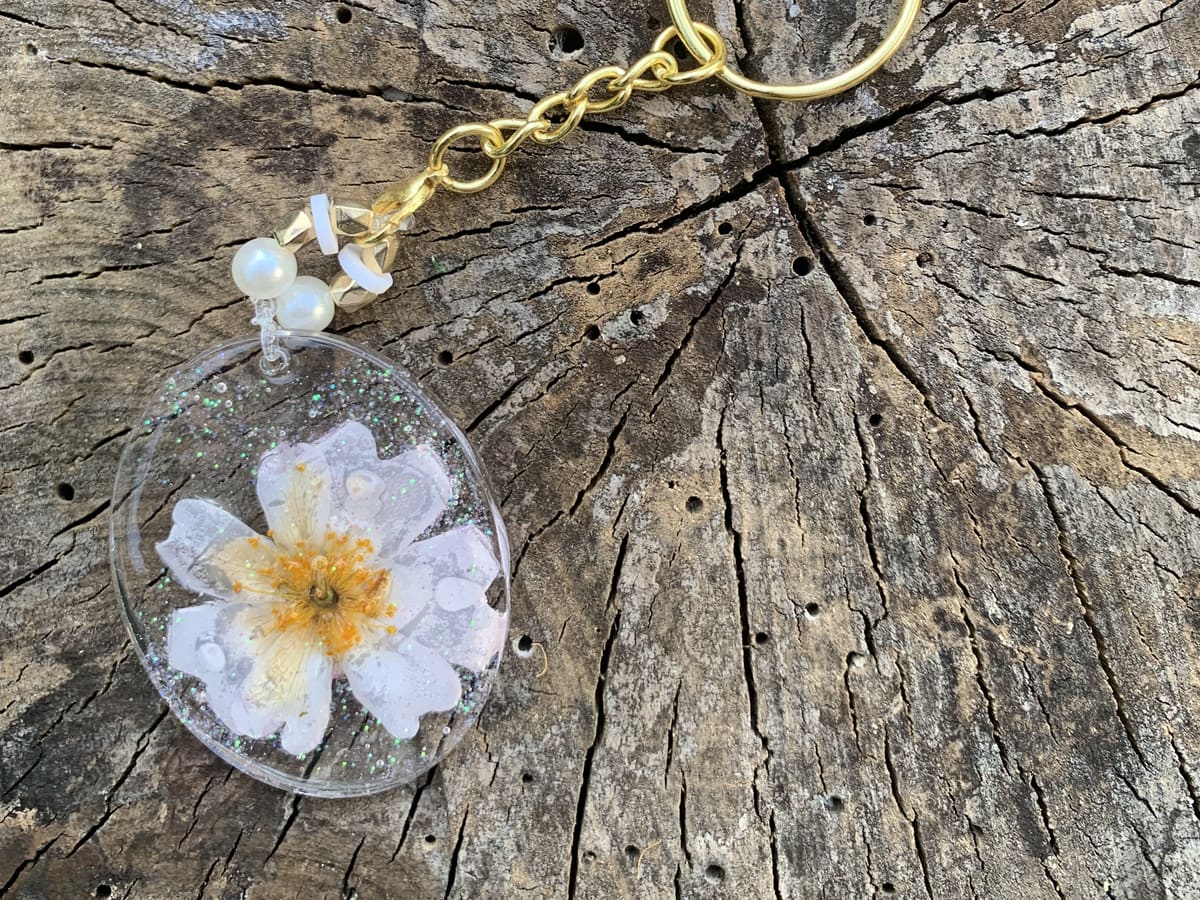 Porte-clé doré avec marguerite blanche séchée
